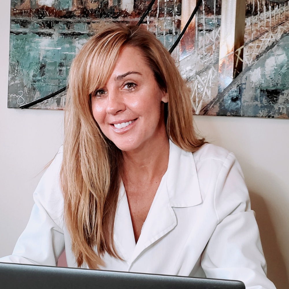 Lynne, esthetician and owner of Palm Beach Skin Co., wearing a white lab coat